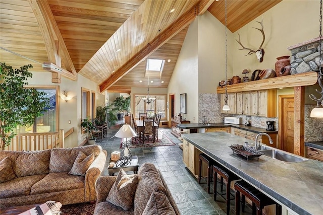 348 Jade Rd, Silverthorne, CO 80498 - living area with high vaulted ceiling, wood ceiling with exposed beams, a chandelier, dark stone finish flooring, and a skylight