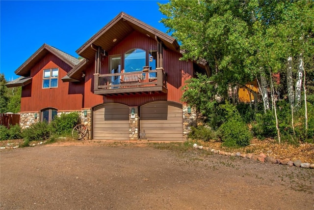 348 Jade Rd, Silverthorne, CO 80498 - view of front of home featuring a balcony, dirt driveway, stone siding, and a garage