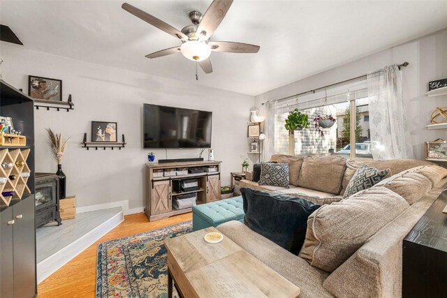 26 Cypress Ct Unit 26, Steamboat Springs, CO 80487 - living area with light wood finished floors, a wood stove, a ceiling fan, and baseboards