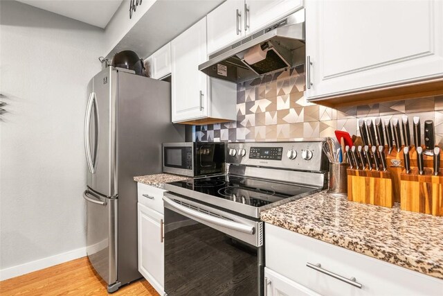 26 Cypress Ct Unit 26, Steamboat Springs, CO 80487 - kitchen featuring under cabinet range hood, stainless steel appliances, baseboards, tasteful backsplash, and white cabinetry