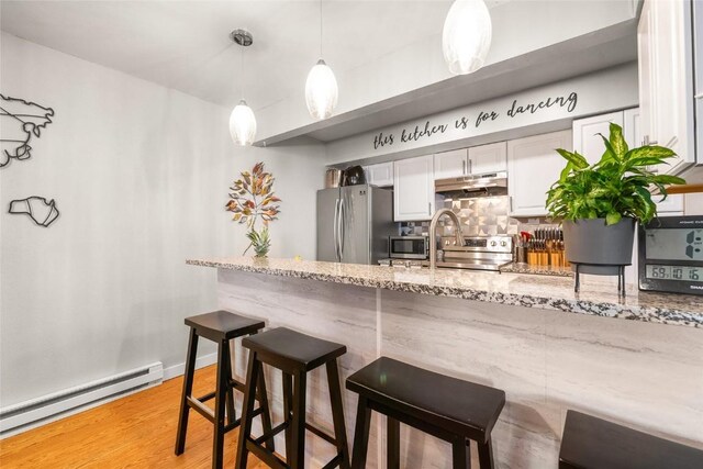 26 Cypress Ct Unit 26, Steamboat Springs, CO 80487 - bar with under cabinet range hood, stainless steel appliances, backsplash, a baseboard heating unit, and hanging light fixtures