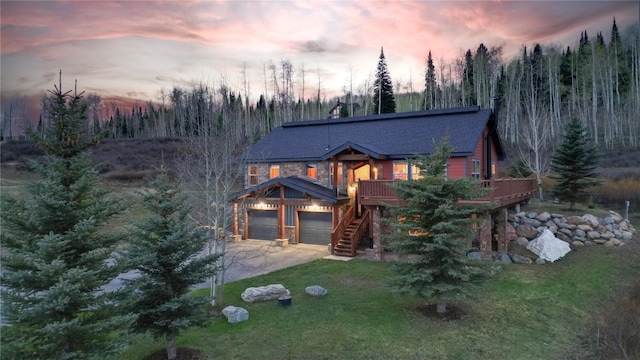 57415 Clara Way, Clark, CO 80428 - back of house at dusk featuring concrete driveway, a yard, stairs, a shingled roof, and a forest view