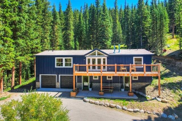 476 County Road 674, Breckenridge, CO 80424 - view of front of house with stone siding, a wooden deck, driveway, a forest view, and a patio area