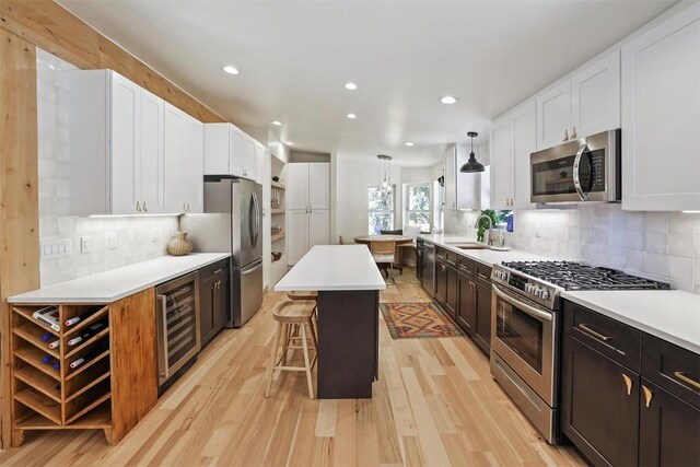 476 County Road 674, Breckenridge, CO 80424 - kitchen featuring appliances with stainless steel finishes, wine cooler, white cabinetry, light wood finished floors, and a kitchen breakfast bar