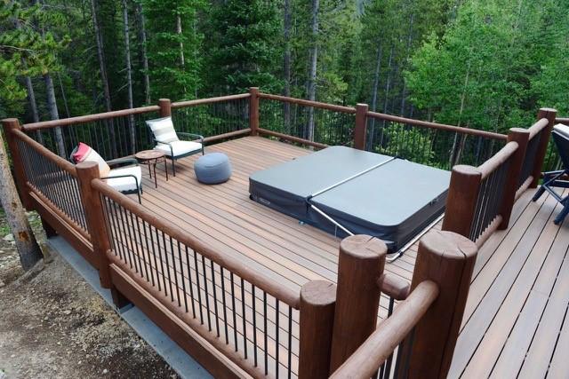 deck featuring a covered hot tub and a forest view