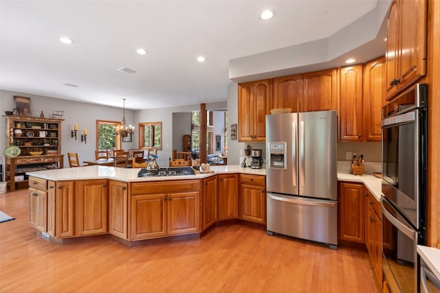 kitchen featuring stainless steel appliances, light wood finished floors, light countertops, a peninsula, and recessed lighting