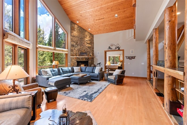 living room featuring baseboards, a stone fireplace, high vaulted ceiling, and wood finished floors