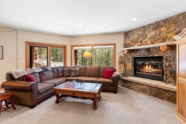 living area featuring plenty of natural light, a stone fireplace, and light carpet