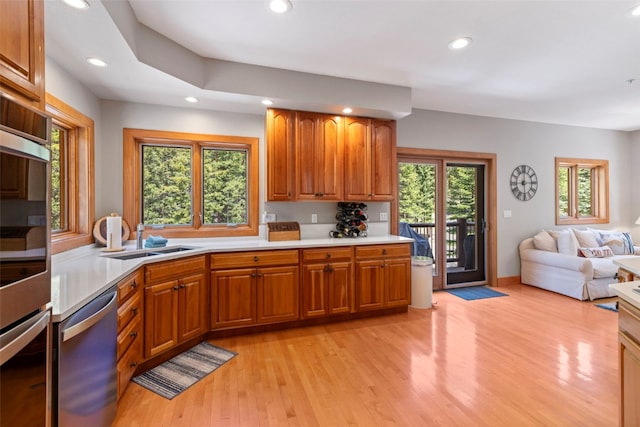 kitchen with dishwasher, light countertops, a sink, and recessed lighting