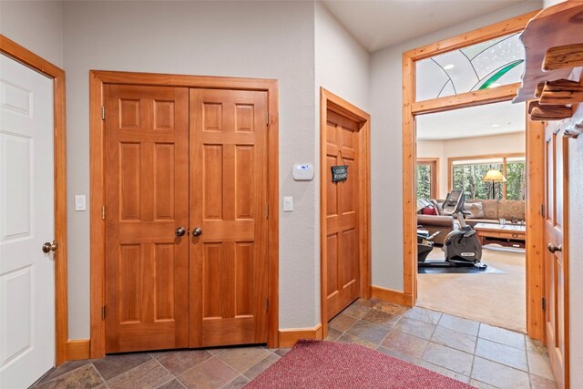 entrance foyer with baseboards and stone tile floors
