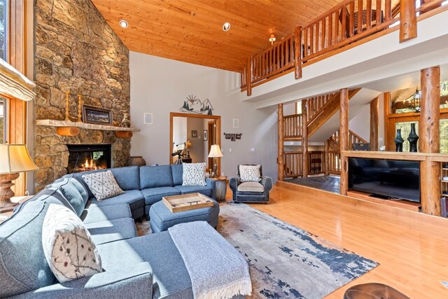 living area featuring wooden ceiling, a high ceiling, wood finished floors, and a fireplace
