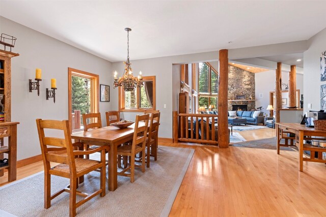 dining space featuring light wood-type flooring, a fireplace, and a chandelier