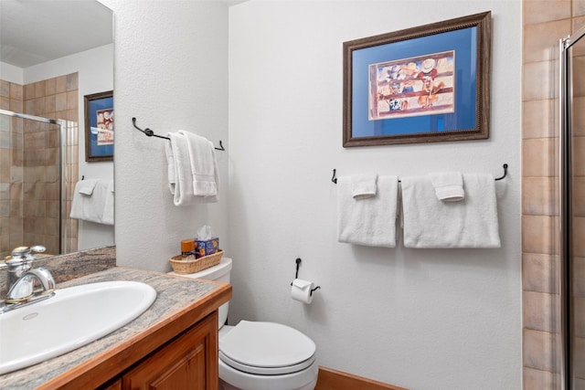 bathroom featuring a shower stall, toilet, and vanity