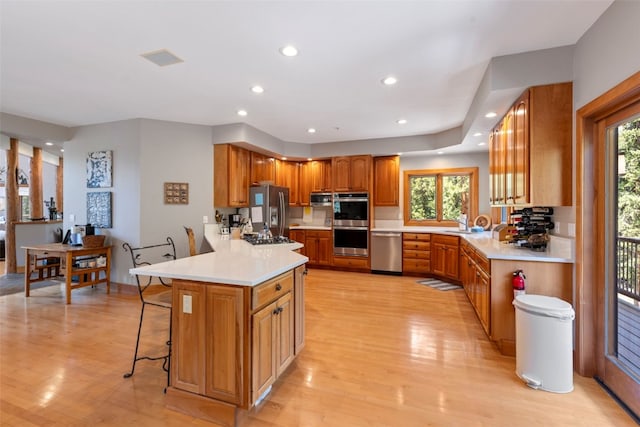 kitchen with a healthy amount of sunlight, stainless steel appliances, a breakfast bar, and light wood-type flooring