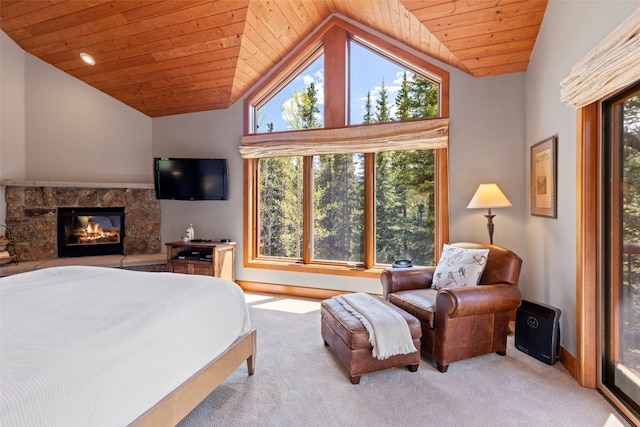 carpeted bedroom featuring baseboards, lofted ceiling, wood ceiling, and a stone fireplace