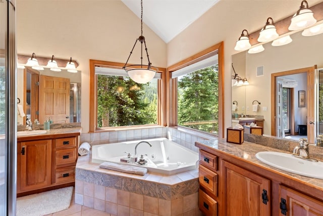 full bath featuring lofted ceiling, visible vents, a tub with jets, and a sink