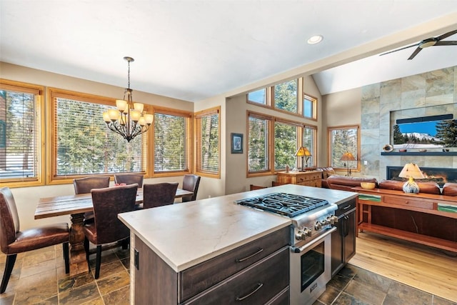kitchen featuring vaulted ceiling, open floor plan, stone tile floors, stainless steel range, and light countertops