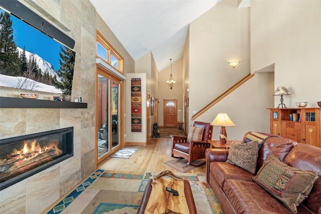 living room with high vaulted ceiling, a chandelier, wood finished floors, and a fireplace