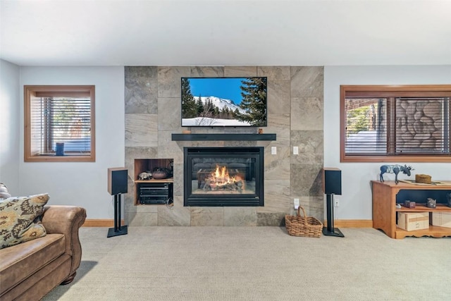 living area featuring a tile fireplace, baseboards, and carpet flooring