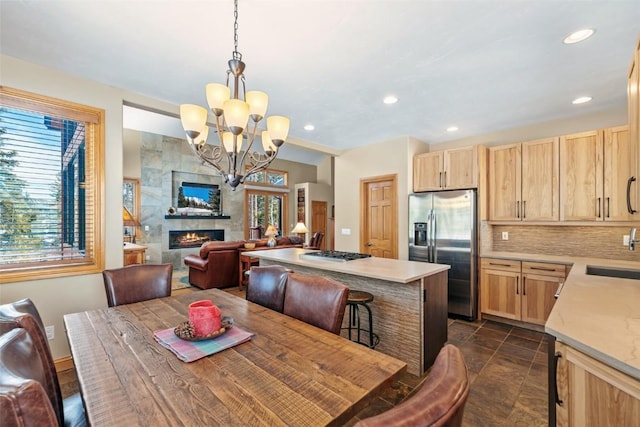 dining room featuring baseboards, an inviting chandelier, recessed lighting, stone finish flooring, and a tile fireplace