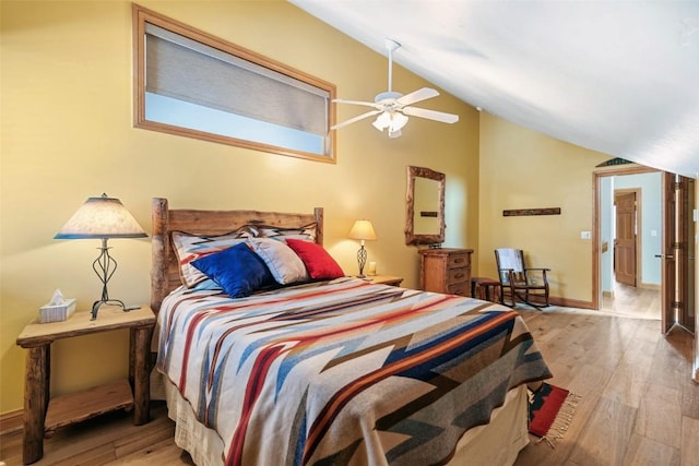 bedroom featuring wood finished floors, lofted ceiling, baseboards, and a ceiling fan