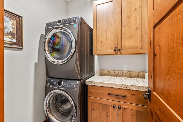 laundry area featuring cabinet space and stacked washer / drying machine