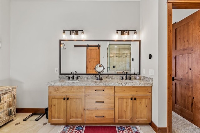 bathroom with double vanity, a shower stall, baseboards, and a sink