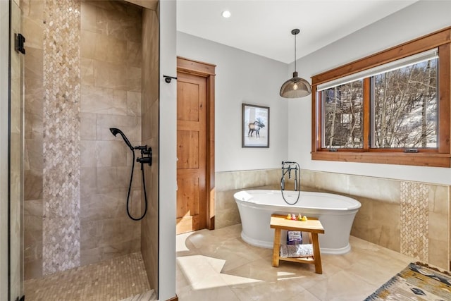 bathroom featuring a wainscoted wall, tiled shower, a freestanding tub, and tile walls