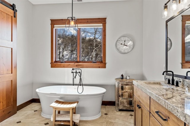 bathroom with a freestanding tub, visible vents, baseboards, and vanity