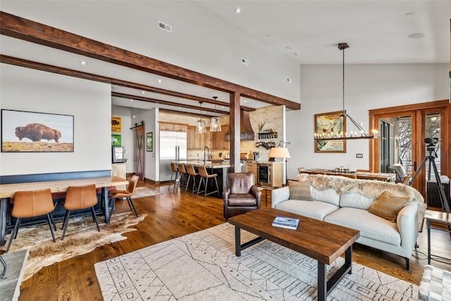 living room featuring a notable chandelier, visible vents, wood finished floors, high vaulted ceiling, and beamed ceiling