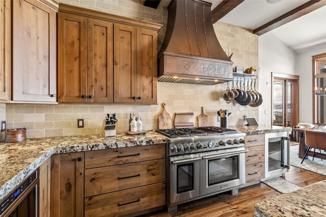 kitchen with vaulted ceiling with beams, wine cooler, premium range hood, wood finished floors, and double oven range