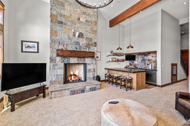 carpeted living area with a stone fireplace, beamed ceiling, a towering ceiling, and a bar