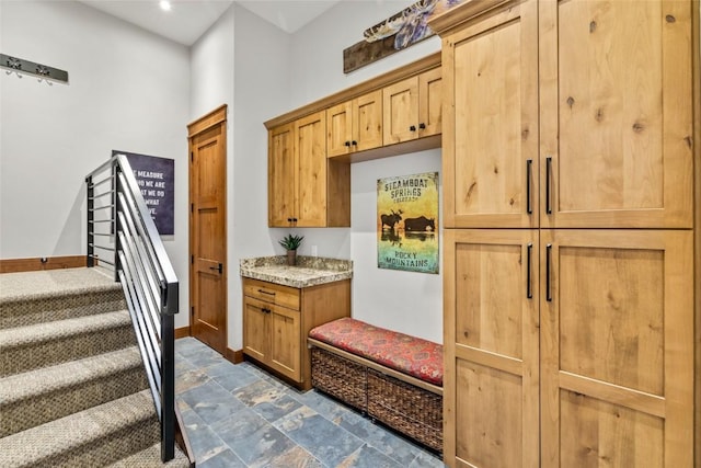 mudroom featuring stone finish flooring and baseboards