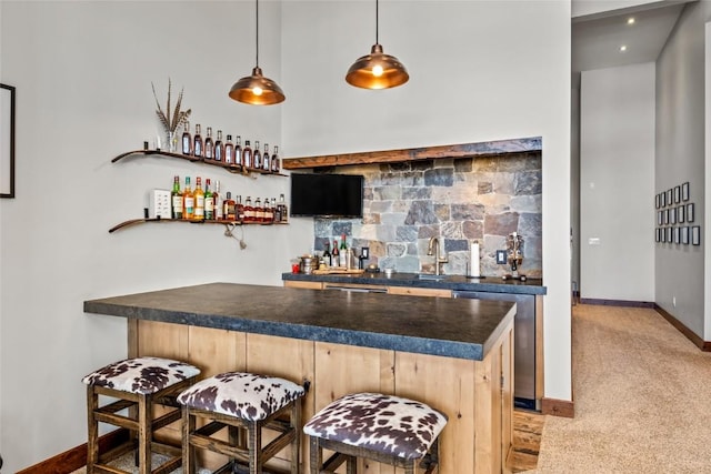 bar featuring a sink, baseboards, stainless steel dishwasher, wet bar, and pendant lighting