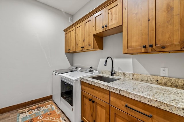 washroom with separate washer and dryer, a sink, cabinet space, and baseboards