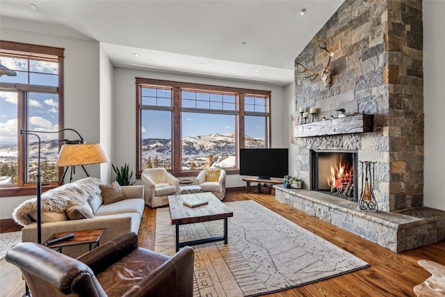 living area with a healthy amount of sunlight, a fireplace, a high ceiling, and wood finished floors