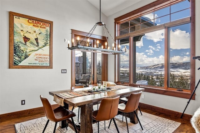 dining area featuring lofted ceiling, a notable chandelier, plenty of natural light, and wood finished floors