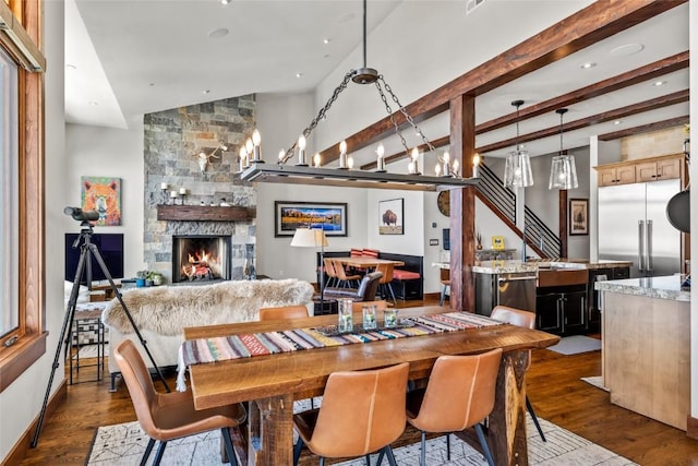 dining area featuring vaulted ceiling with beams, recessed lighting, dark wood-style flooring, a fireplace, and stairs