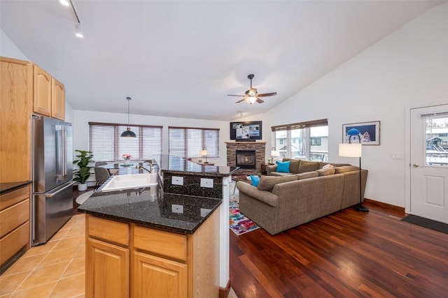 kitchen with high end fridge, vaulted ceiling, a ceiling fan, a sink, and a center island
