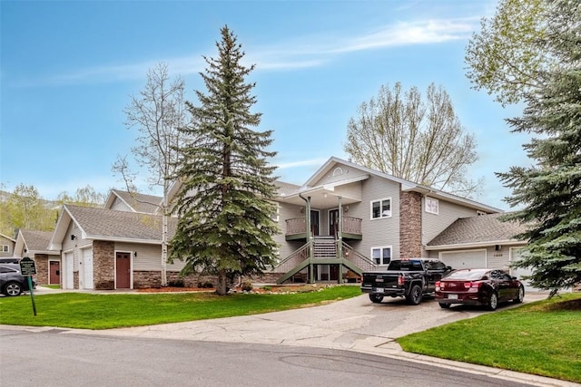 1485 Mustang Run Unit A, Steamboat Springs, CO 80487 - view of front facade with stone siding, asphalt driveway, an attached garage, a front yard, and stairway