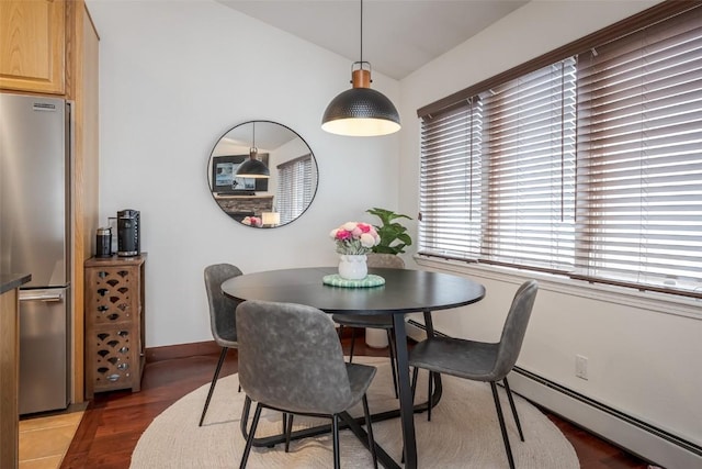 dining area featuring a baseboard radiator, vaulted ceiling, baseboards, and light wood-type flooring
