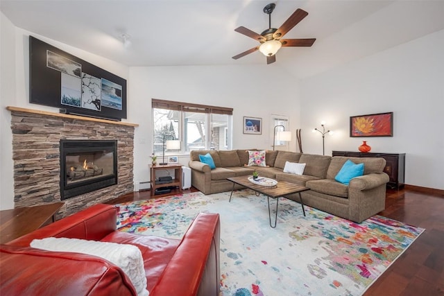 living room featuring wood finished floors, a baseboard heating unit, ceiling fan, a fireplace, and baseboards