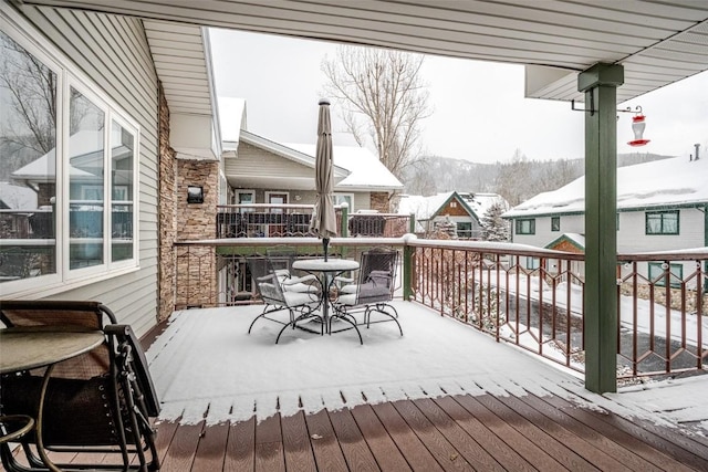 snow covered deck featuring outdoor dining space and a mountain view