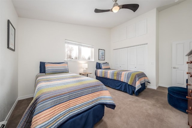 carpeted bedroom featuring baseboard heating, baseboards, a closet, and a ceiling fan
