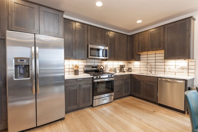 1080 Blue River Pkwy Unit 203, Silverthorne, CO 80498 - kitchen featuring light countertops, a sink, light wood-style floors, dark brown cabinetry, and appliances with stainless steel finishes