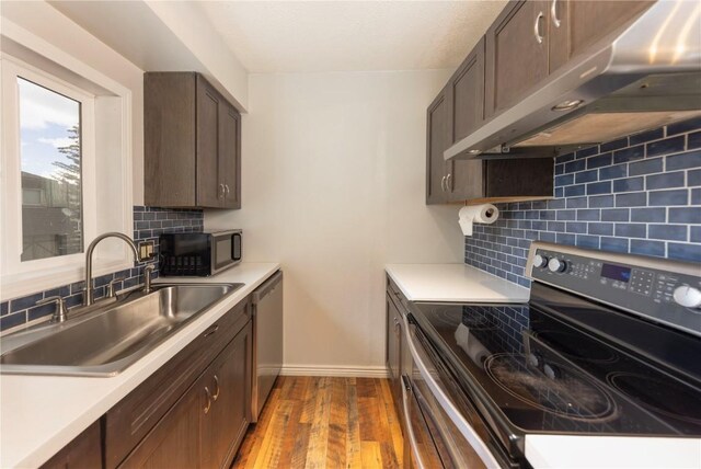 6950 Ryan Gulch Rd Unit 6950, Silverthorne, CO 80498 - kitchen featuring stainless steel appliances, under cabinet range hood, a sink, baseboards, and wood finished floors