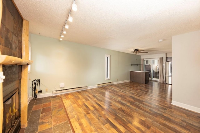 6950 Ryan Gulch Rd Unit 6950, Silverthorne, CO 80498 - unfurnished living room featuring a baseboard radiator, a textured ceiling, a large fireplace, ceiling fan, and baseboards