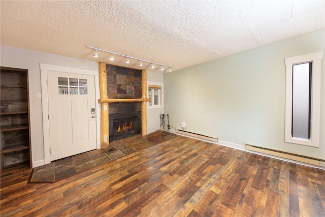 6950 Ryan Gulch Rd Unit 6950, Silverthorne, CO 80498 - unfurnished living room with a baseboard heating unit, wood finished floors, a large fireplace, rail lighting, and a textured ceiling