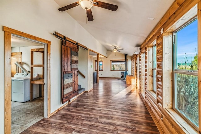 259 Falcon Rd, Como, CO 80432 - hallway featuring washer / dryer, vaulted ceiling, wood finished floors, rustic walls, and a barn door