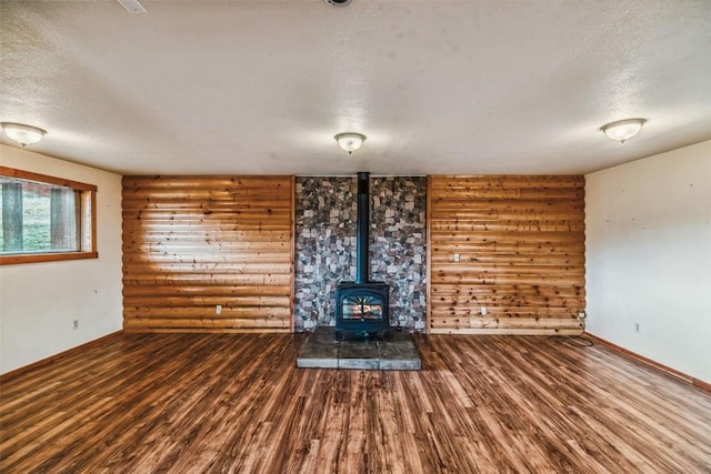259 Falcon Rd, Como, CO 80432 - unfurnished living room featuring a textured ceiling, a wood stove, wood finished floors, and baseboards